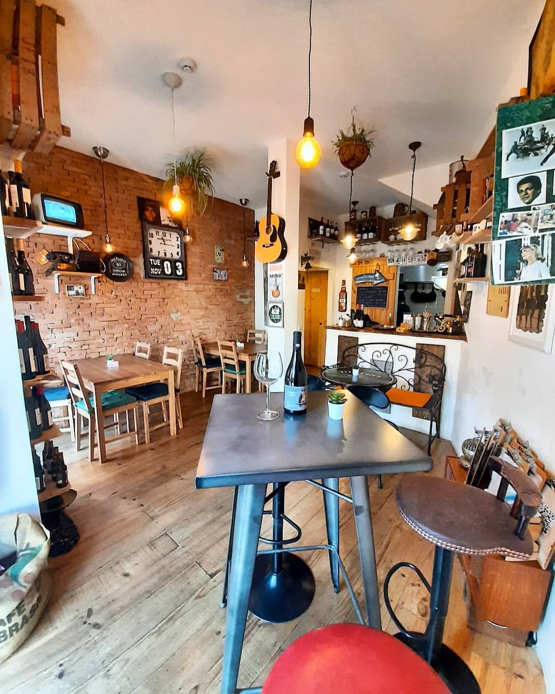 Sala do Café Vintage com parede de tijolo, mesas de madeira, candeeiros suspensos e uma guitarra na parede